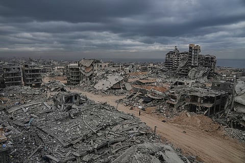 Displaced Palestinians walk amid destroyed buildings in the Shati refugee camp in Gaza City, Sunday, Oct. 12, 2025, after Israel and Hamas agreed to a pause in their war and the release of the remaining hostages.