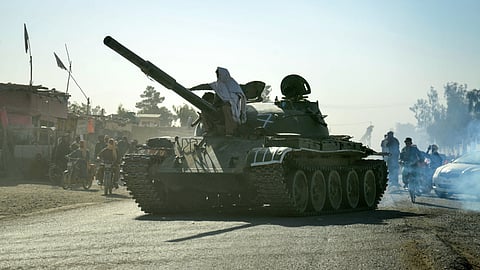 Taliban security personnel on a Soviet-era tank are followed by motorcyclists as they ride towards the border, as clashes take place between Taliban security personnel and Pakistani border forces, in the Spin Boldak district of Kandahar Province on October 15, 2025.