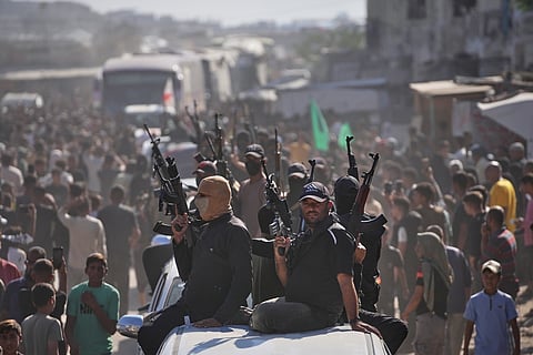 Hamas gunmen on pickup trucks escort buses carrying freed Palestinian prisoners as they are greeted following their release from Israeli jails under a cease-fire agreement between Hamas and Israel, in Khan Younis, southern Gaza Strip, Monday, Oct. 13, 2025.