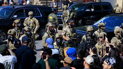 Government officials watch protesters gathering in Chicago, Tuesday, Oct. 14, 2025.