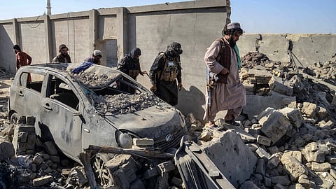 Taliban security personnel walk past a damaged car in the Spin Boldak district of Kandahar province on October 16, 2025, a day after the cross-border clashes between Afghanistan and Pakistan.