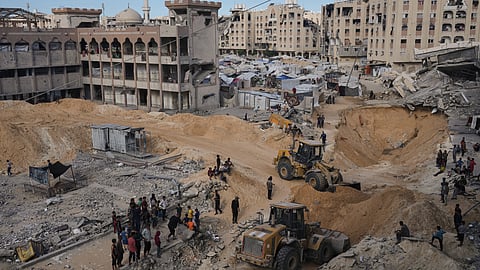 Palestinians watch members of the Hamas militant group searching for bodies of the hostages in an area in Hamad City, Khan Younis, in the southern Gaza Strip, Saturday, Oct. 18, 2025