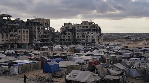 A tent camp for displaced Palestinians sits adjacent to destroyed homes and buildings in Khan Younis, Gaza Strip, Saturday, Oct. 18, 2025.
