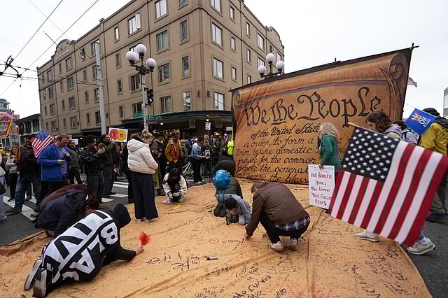People are signing a giant Constitution as they take part in a "No Kings" protest Saturday, Oct. 18, 2025, in Seattle.