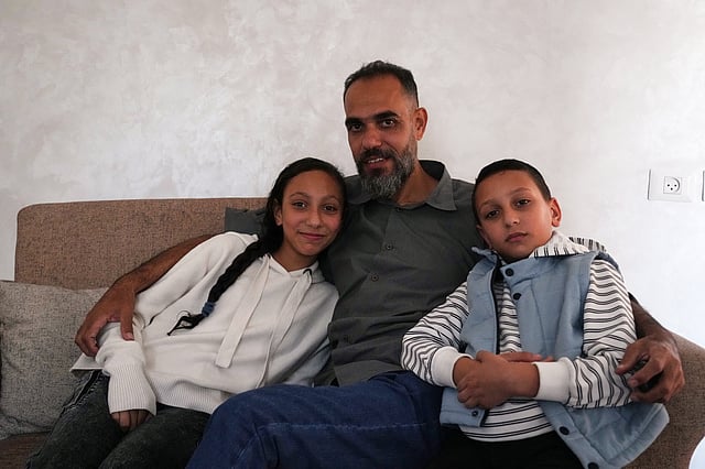 Palestinian medical technician Mohammed Abu Moussa, 45, who was released from Israeli detention after 20 months, poses for a photo with his children, Jourie and Hamid, in Deir al-Balah, Gaza, Saturday, Oct. 18, 2025.