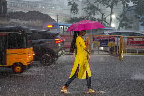 A woman walks with an umbrella on a road during heavy rainfall, in Chennai, Tuesday, Oct. 21, 2025.