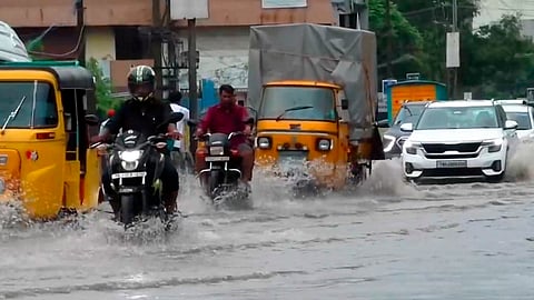 Commuters make their way through a waterlogged road following heavy rainfall, in Avadi, Tamil Nadu, Wednesday, Oct. 22, 2025.