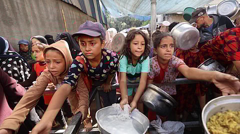 Palestinian children gather to receive food portions from a charity kitchen in the Nuseirat refugee camp, located in the central Gaza Strip, on October 21, 2025, a week after a ceasefire came into effect.