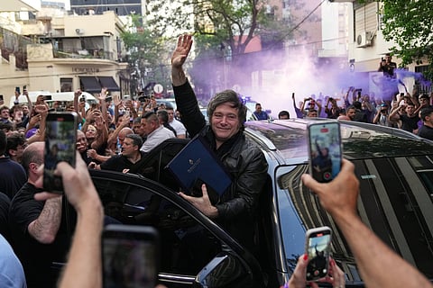 Argentine President Javier Milei waves to supporters upon arriving at a hotel in Rosario, Argentina, Thursday, Oct. 23, 2025.