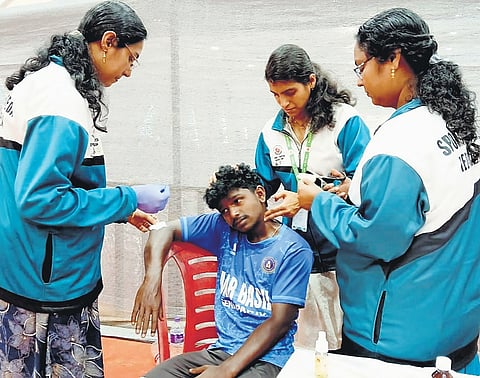 Dr Dhiya and Dr Resmi S of Sports Ayurveda attending to the neck sprain and elbow wound of a KhoKho participant at Central Stadium during the 67th Kerala School Sports Meet at Chandrasekharan Nair Stadium on Monday