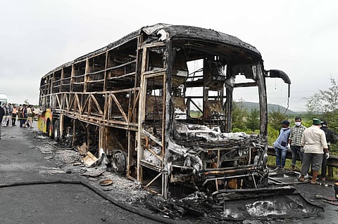 Police personnel investigate the spot after a Hyderabad-bound private bus caught fire following a collision with a two-wheeler, near Chinnatekur in Kurnool district, Andhra Pradesh.
