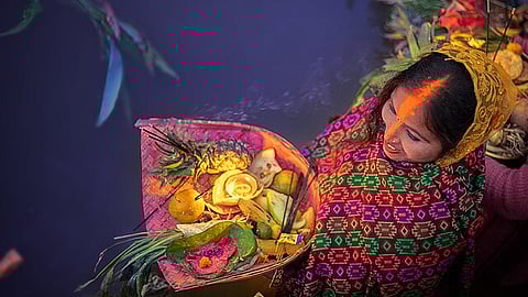 Women making offerings of thekua and fruits to the Sun god during Chhath Puja