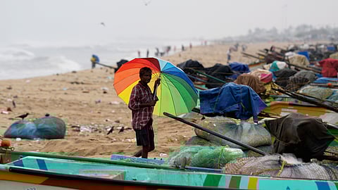 A person looks at anchored fishing boats ahead of the landfall of Cyclone 'Montha', at Marina Beach in Chennai, Tuesday, Oct. 28, 2025.