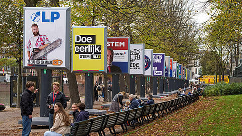 People enjoy the autumn weather next to some of the election billboards of 26 of the 27 political parties participating in the Oct. 29 general elections in The Hague, Netherlands, Wednesday, Oct. 22, 2025.