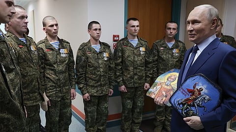 President Vladimir Putin holds Russian Orthodox icons as he meets with soldiers wounded in action in Ukraine at the Mandryk Central Military Clinical Hospital, in Moscow, Russia, Wednesday, Oct. 29, 2025.