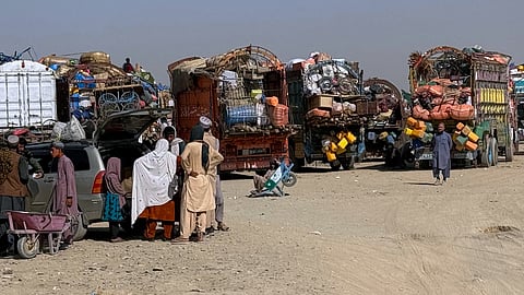 Afghan refugees gather beside trucks loaded with their belongings as they wait their turn to leave for their homeland through a border crossing point which partially opens following Oct.19 ceasefire, on the outskirts of Chaman, a border town on the Pakistan Afghan border, Wednesday, Oct. 29, 2025.