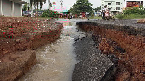 A road cave-in on the Vepagunta–Pinagadi stretch, Visakhapatnam, worsened by pond overflow after Cyclone Montha, has left commuters struggling with flooding, damaged roads, and poor safety measures.