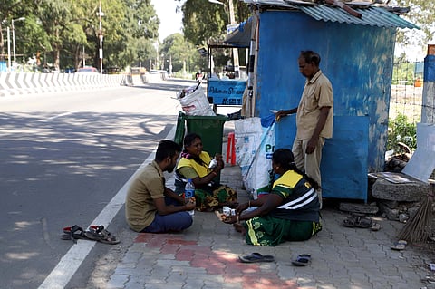 Sanitary workers are seen taking a break under the shade of a tree on Nanjundapuram Road in Coimbatore on Saturday.