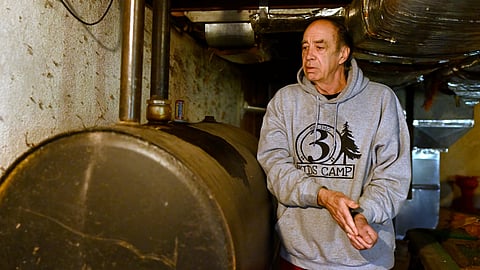 Mark Bain, who is part of the Low Income Home Energy Assistance Program, rubs his hands together as he checks the level on his oil at home in hopes that he will have enough oil to outlast the shutdown, in Bloomfield, Conn., Monday, Oct. 27, 2025.