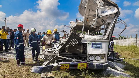 Police and firefighters look at the wrecked remains of a public transport bus after a head-on collision with a tipper lorry carrying gravel, in Rangareddy district, Telangana, Monday, Nov. 3, 2025.