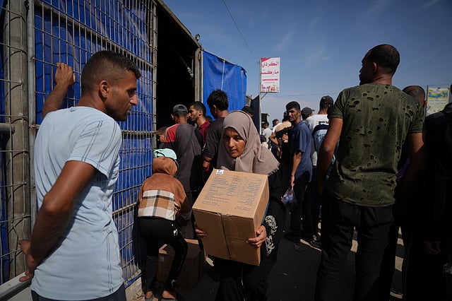 A Palestinian woman carries a box of food from the World Food Programme (WFP) after collecting it in Khan Younis, southern Gaza Strip, Sunday, Nov. 2, 2025.