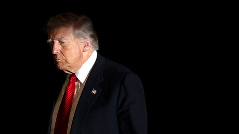 US President Donald Trump is illuminated by a camera flash as he walks across the South Lawn of the White House on Sunday, Nov. 2, 2025, in Washington, after returning from a trip to Florida.