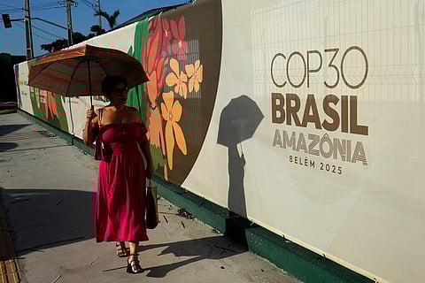 A woman walks past a sign for the COP30 U.N. Climate Summit, in Belem, Para state, Brazil, Tuesday, November 4, 2025.