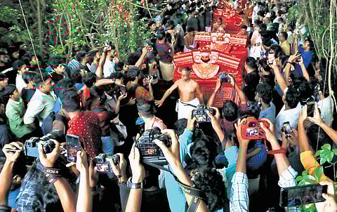 Vloggers and photographers jostle for space to click theyyam performers during Madayi Kavu Kalasham