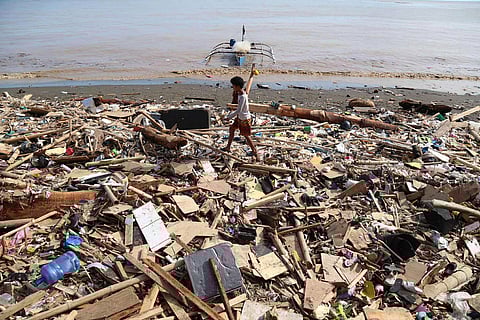 Residents walk along debris along a shoreline after Typhoon Kalmaegi caused devastation in communities at Talisay City, Cebu province, central Philippines, Wednesday, Nov. 5, 2025.