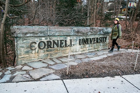 A woman walks by a Cornell University sign on the Ivy League school's campus in Ithaca, New York, Jan. 14, 2022.