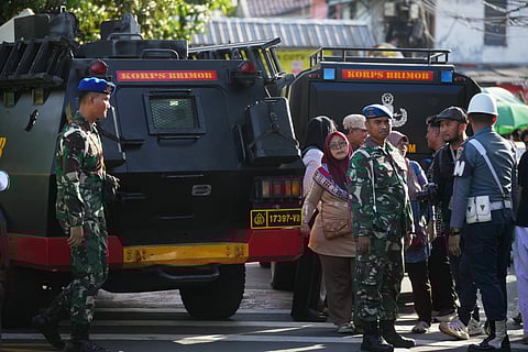 Curious onlookers look on as military personnel stand guard near a school where explosions reportedly occurred, in Jakarta, Indonesia, Friday, Nov. 7, 2025.