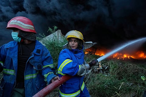 Female firefighter Syeda Masooma Zaidi, right, with her team member spray water to extinguish when a fire broke out in a storage facility packed with truck and car tyres, outskirts of Karachi, Pakistan, Thursday, Oct 30, 2025.