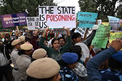 Demonstrators hold posters and shout slogans during a protest demanding the government take action to reduce air pollution in New Delhi on November 9, 2025.