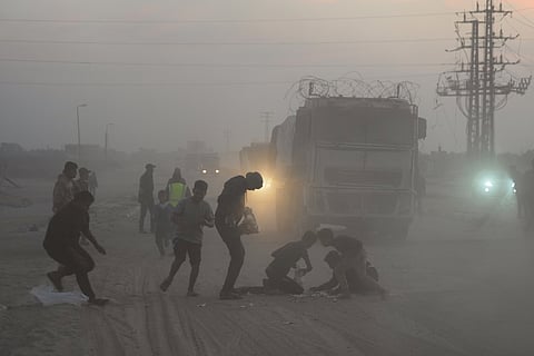 Palestinians rush toward trucks carrying aid from the World Food Programme (WFP) as they drive through Deir al-Balah in central Gaza.