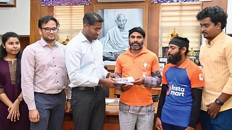 Thrissur District Collector Arjun Pandian, who is also the district election officer, hands over the first set of pamphlets to an online food delivery partner on Tuesday.