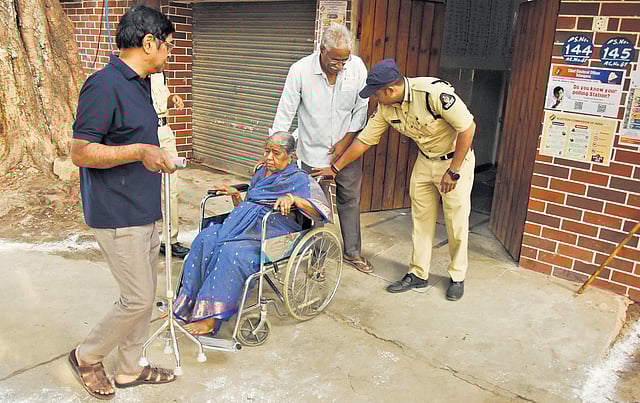 A cop helps a woman on a wheelchair exit a polling booth at MMCC Talent High School in Rahmatnagar, Hyderabad on Tuesday.