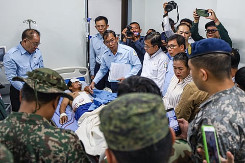 In this photo released by Agence Kampuchea Press (AKP), an injured man, rear center, is visited by members of the ASEAN's observer team (AOT) in a hospital in Prey Chan, a border village to Thailand, in Banteay Meanchey province, Cambodia, Thursday, Nov. 13, 2025.