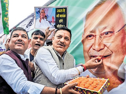 JD(U) members pose alongside a flex board of Nitish Kumar, in Patna on Friday.