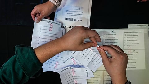 An electoral worker prepares demonstration ballots inside the old Mapocho train station that is now a cultural center to be used as a polling station for the general election in Santiago, Chile, Friday, Nov. 14, 2025.