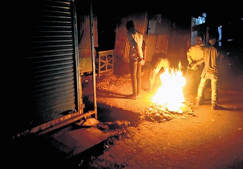 Locals warm themselves near a bonfire along the roadside at Jeypore