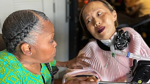 This March 2024 photo provided by Sandy Ho shows Yomi Young, left, speaking with Alice Wong at Wong’s 50th birthday party in San Francisco.