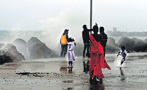People enjoying the cool weather at Kasimedu harbour in Chennai, as the waves crash against the groyne on Monday