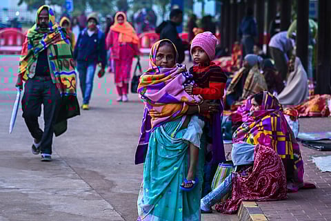 People wrap themselves with shawls and winter clothes to get rid of cold while waiting outside AIIMS as temperature dips in Bhubaneswar on Monday.