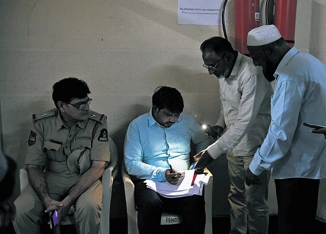 (From top) Before their trip to Saudi Arabia, victims’ relatives get their documents checked at the Hajj House in Hyderabad; officials verify travel documents under flashlight from a mobile phone at Hyderabad on Tuesday | Vinay Madapu