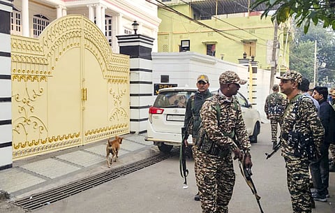 Security personnel stand guard outside a property during a raid conducted by the Enforcement Directorate (ED), in Dhanbad, Jharkhand, on November 23, 2025