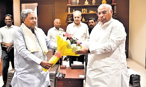 Chief Minister Siddaramaiah greets AICC president Mallikarjun Kharge in Bengaluru on Saturday.