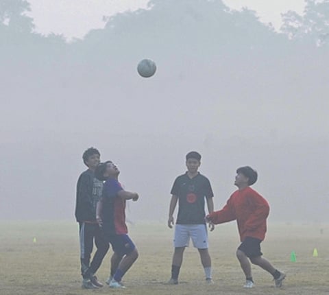 Youths play football amid air pollution smog at a garden in New Delhi on Saturday.