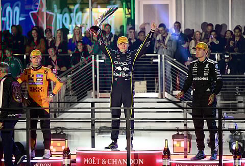 Red Bull Racing's Max Verstappen (C) celebrates with second place finisher McLaren's Lando Norris (L) and third place finisher Mercedes' driver George Russell (R) on the podium after the Las Vegas Formula One Grand Prix on November 22, 2025.