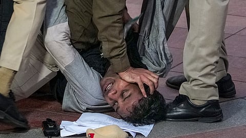 Police personnel detain a protestor during a protest against worsening air quality in the national capital, near the India Gate, in New Delhi, Sunday, Nov. 23, 2025.