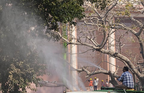An NDMC worker sprays water on trees to curb dust particles amid air pollution in the national capital, in New Delhi, Wednesday, Nov. 26